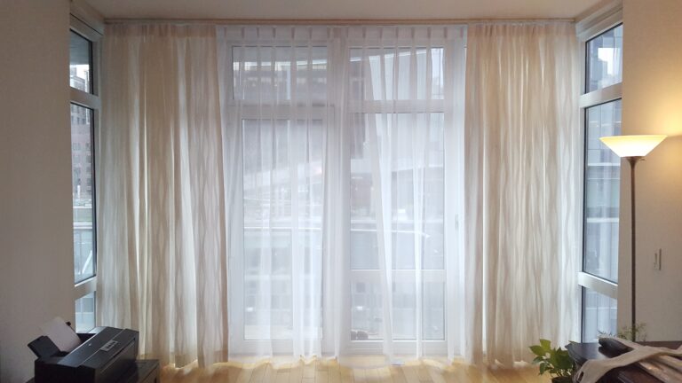 Sheer drapery across a bay window in a living room