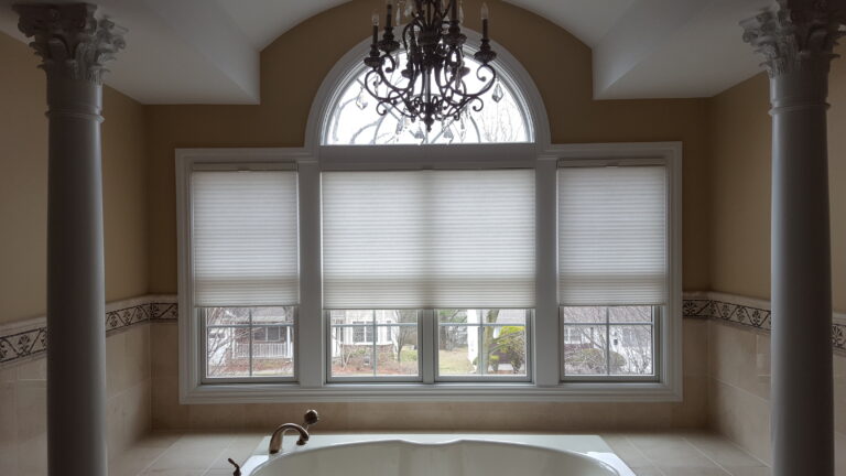 Cellular honeycomb shades in Aspen Snow fitted across a living room bay window in a Bergen County home