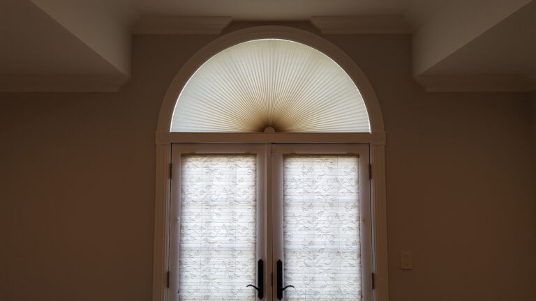 Duette Panache honeycomb shades with a fitted arch above a living room window