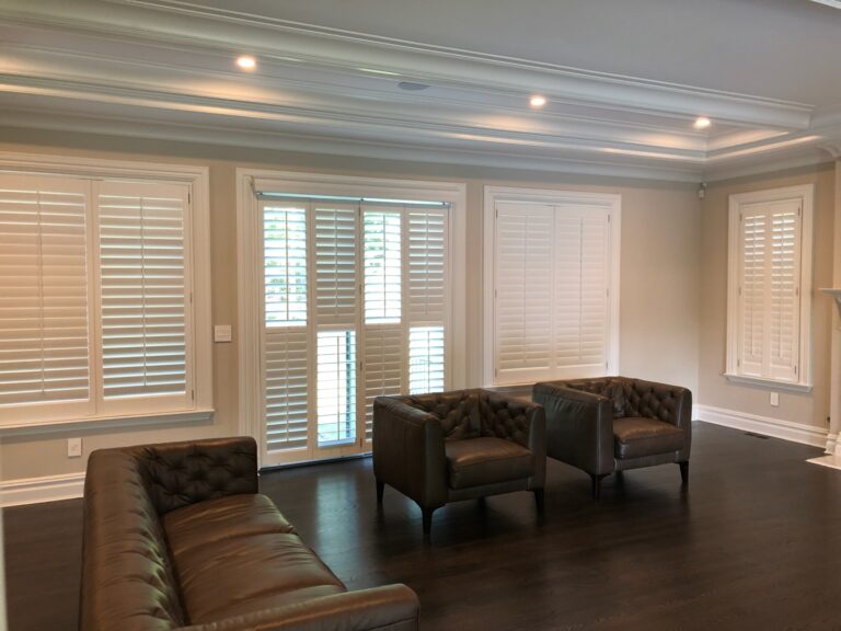 NewStyle hybrid plantation shutters with three and a half inch louvers in a living room with leather armchairs