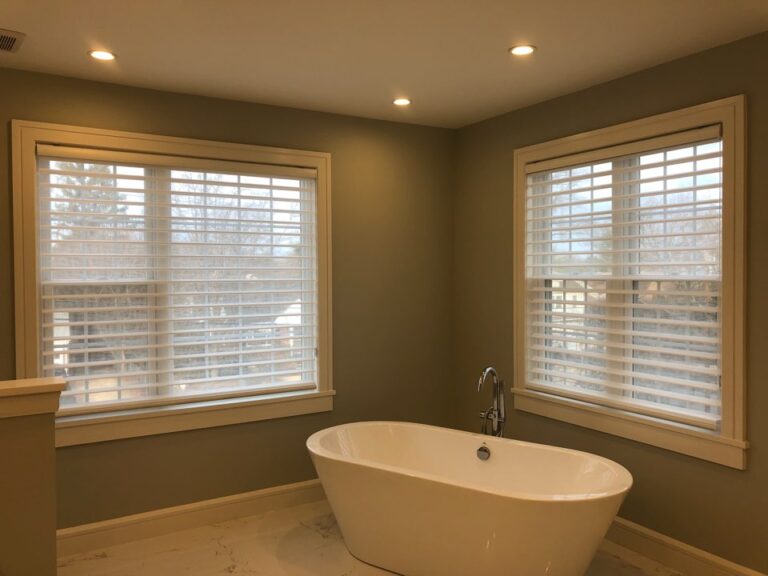 White zebra shades on three bathroom windows around a freestanding tub