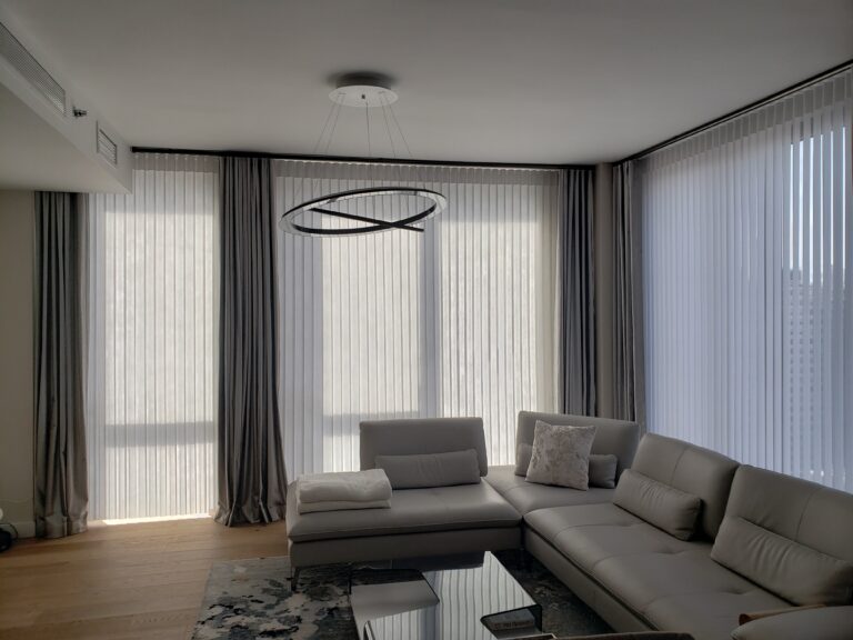 Vertical sheers across a living room window wall behind a sofa