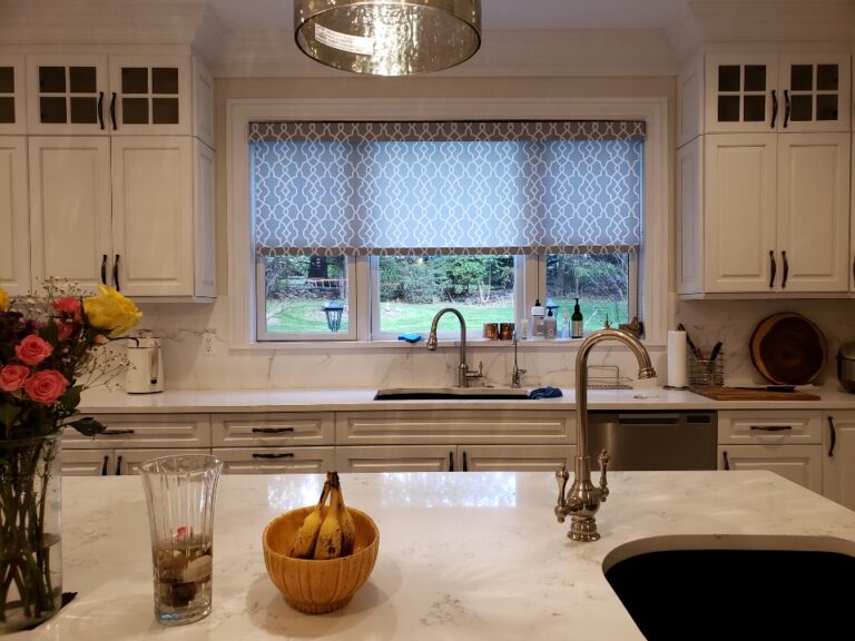 Patterned grey trellis roman shade with a square cassette above a kitchen sink