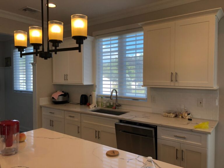 White zebra shades on two kitchen windows above a run of cabinets