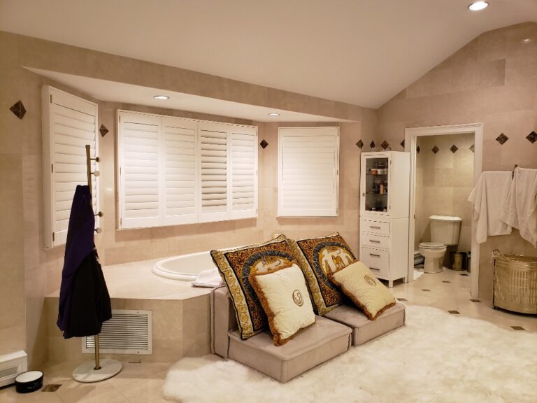 Polysatin plantation shutters on a bathroom bay window and side window, one panel hinged open
