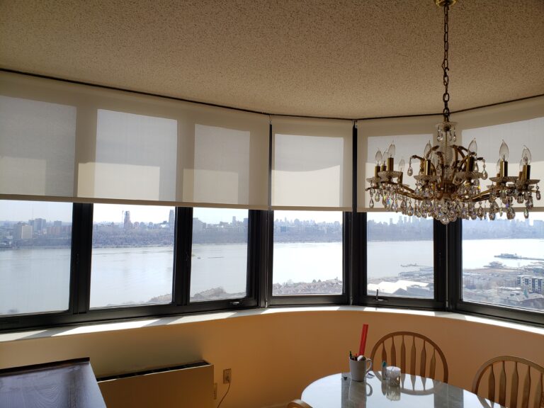 Roller shades fitted across a dining room bay window in a Bergen County home