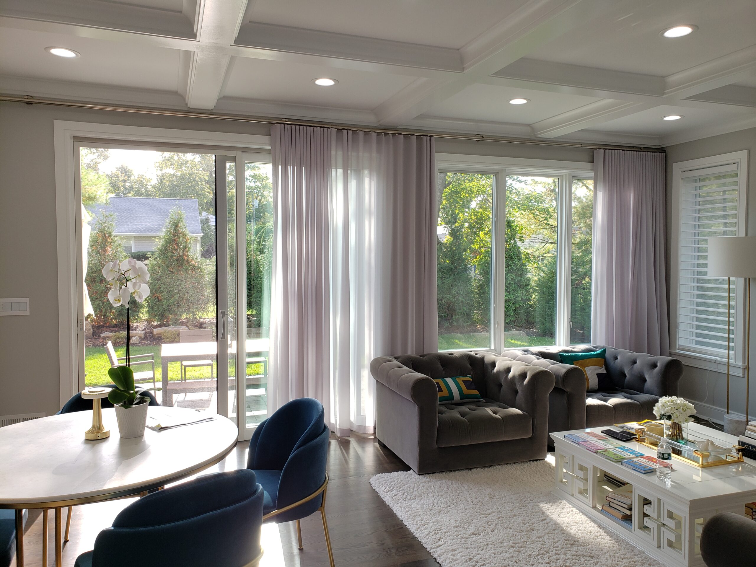 Taupe ripplefold drapery and white sheers across a sliding glass door in an open plan living and dining room