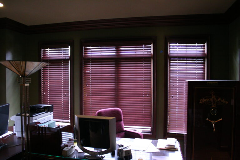 Wood blinds on three office windows behind a desk
