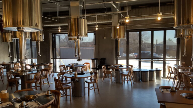 Dark chocolate solar screen shades on a tall window, view visible through the weave