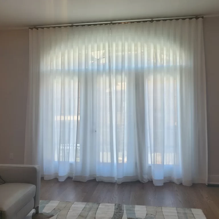 Sheer white drapery across a full wall of windows in a minimalist living room