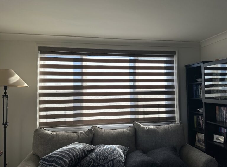 Zebra shades across a wide living room window with the alternating sheer and solid bands clearly visible