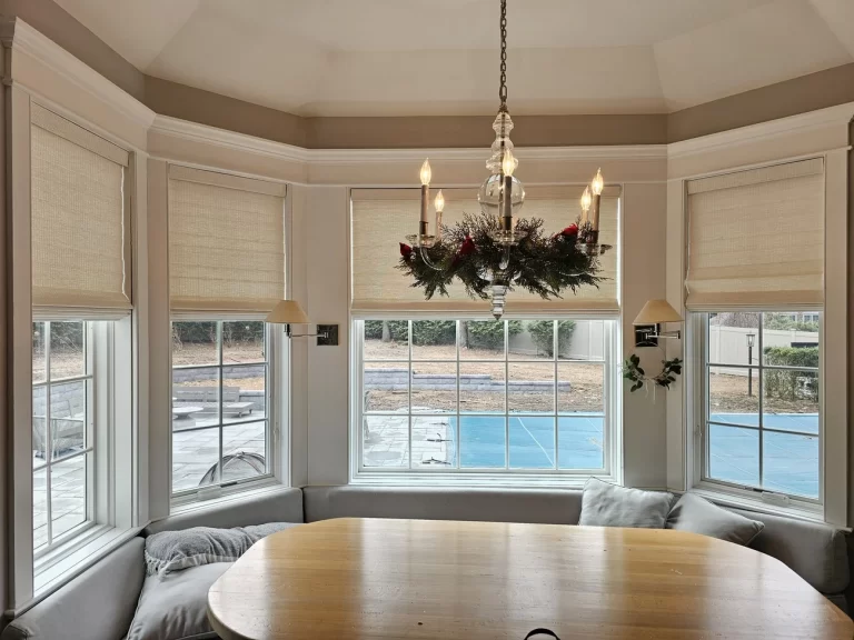 Woven wood shades across a bay window dining nook