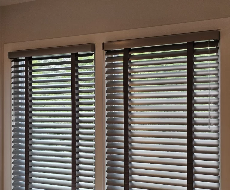 Aluminum blinds with dark cloth ladder tape, slats tilted open, on two side-by-side windows