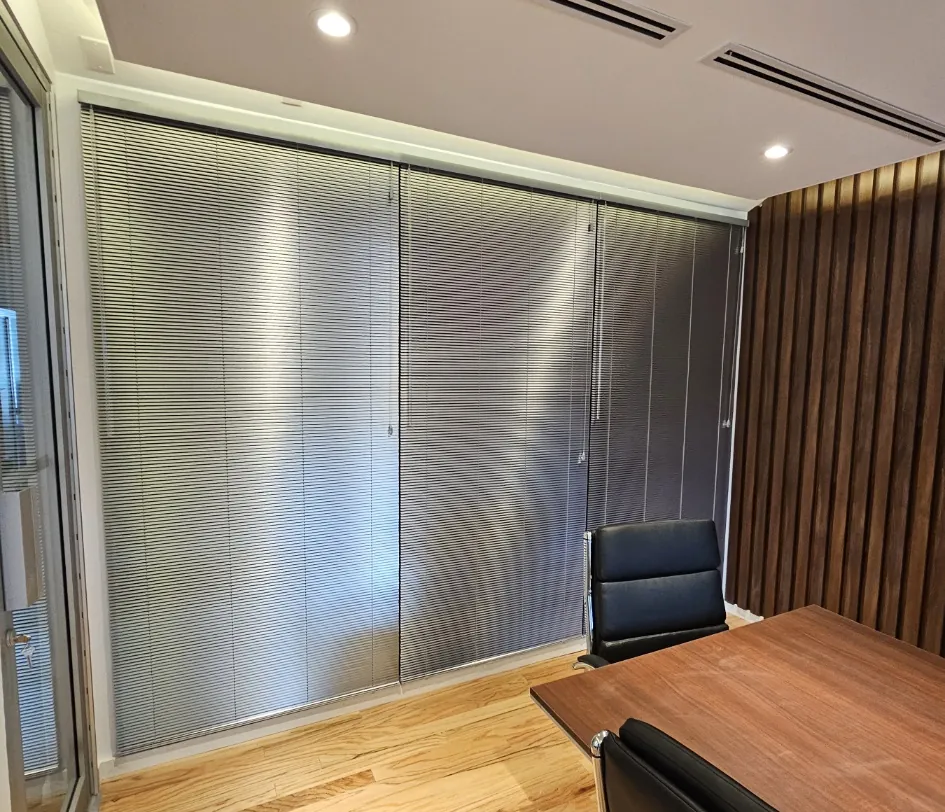 Silver aluminum mini blinds lowered floor to ceiling in an office conference room
