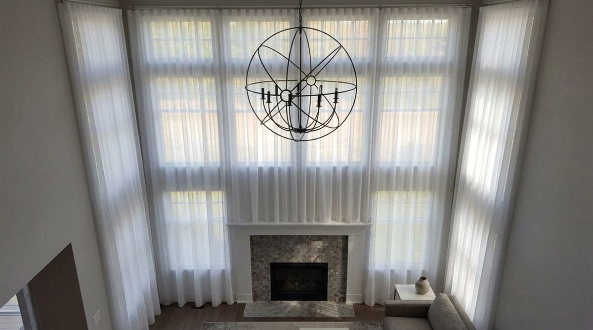 Soft even daylight filtering through a lowered sheer shade into a calm living room, gentle light falling across the floor and a sofa