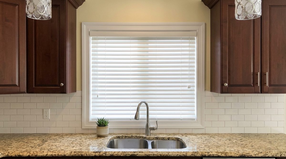 A small square kitchen window fitted with a white horizontal blind, a window far too small for a vertical blind