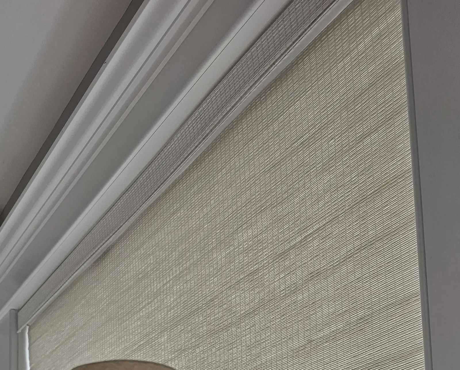 A woven wood shade and its matching valance set under white crown molding