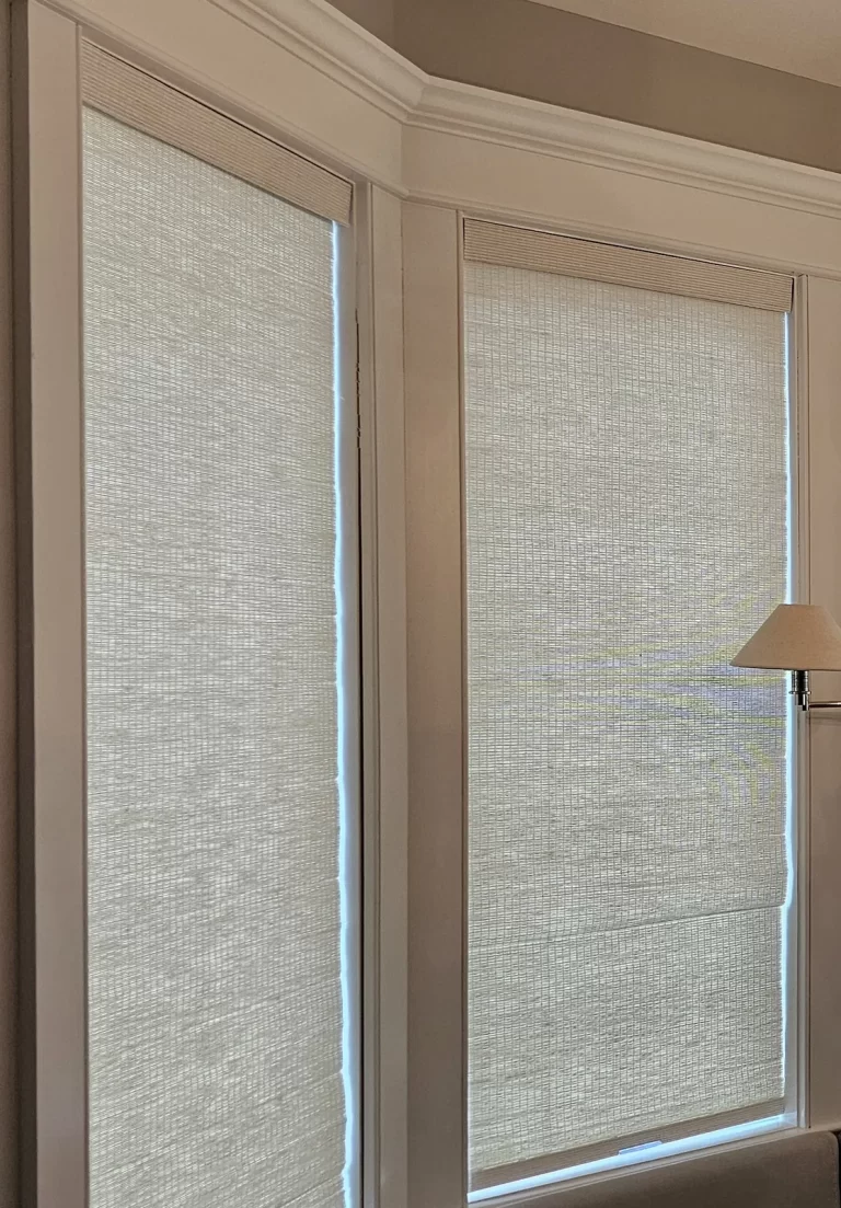 Woven wood shades lowered on two angled windows of a bay, softening the daylight