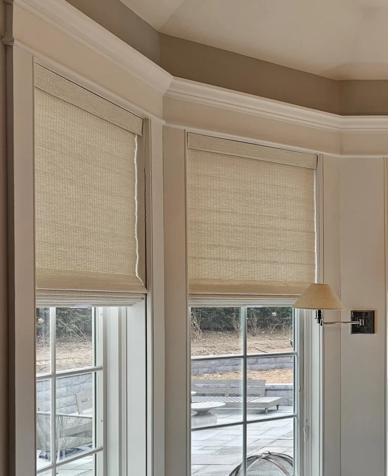 Natural woven wood shades raised on two windows of a bay window breakfast nook