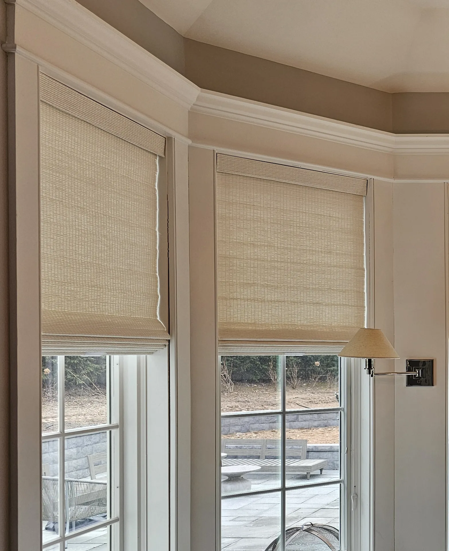 Natural woven wood shades raised on two windows of a bay window breakfast nook